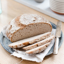 Loaf of gluten-free vegan sourdough on plate with butter knife