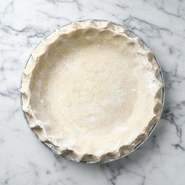 Unbaked pie crust in a glass pie dish on a marble surface