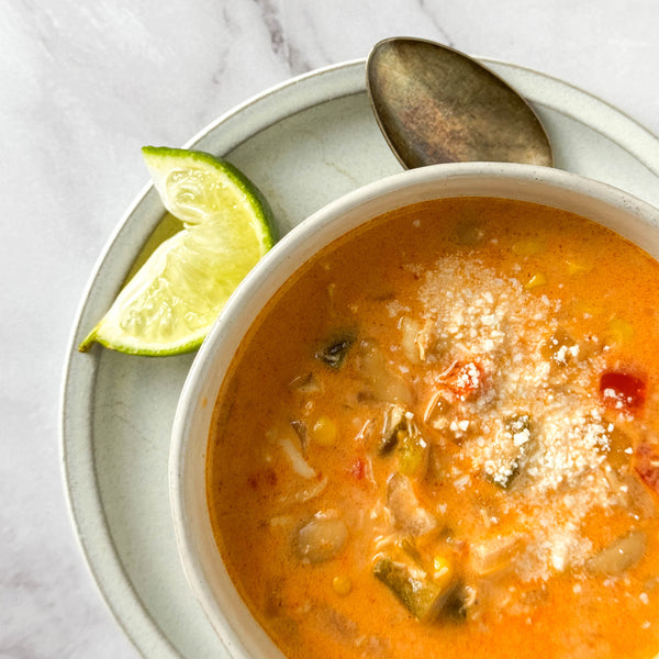  bowl of soup with a lime wedge and spoon on a marble surface
